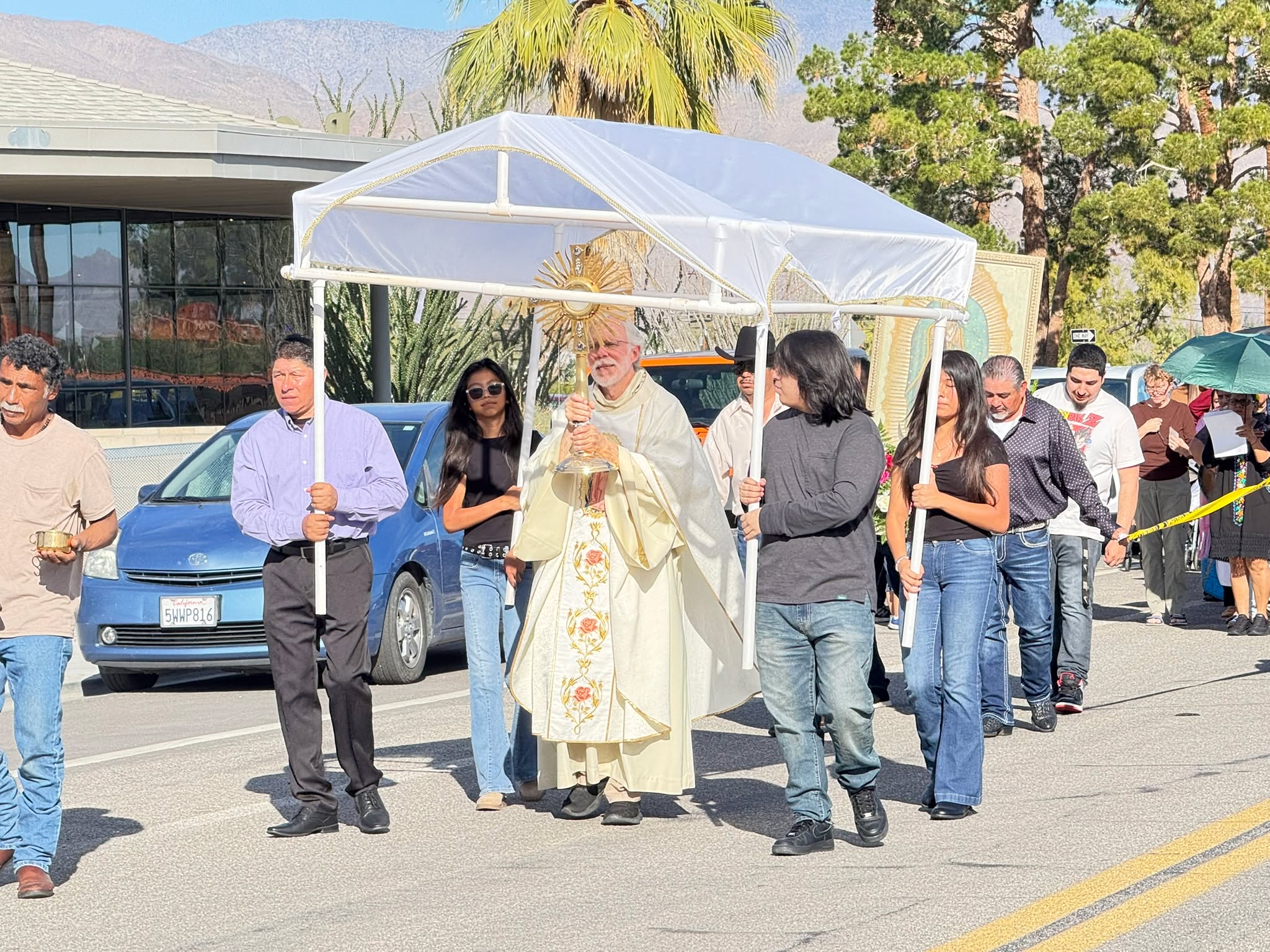 Borrego Springs observed the annual Guadalupe Procession on Saturday, December 13, as community members marked the occasion with prayer, music, and a public walk led by Fr. Anthony “Tony” Stanonik of St. Richard’s Catholic Church. The route started at Christmas Circle, continued past the Borrego Art Institute and the Borrego Springs Post Office, and made its way to St. Richard’s Catholic Church.
The observance centers on Our Lady of Guadalupe, the name given to the Virgin Mary following her 1531 apparition to Saint Juan Diego in Mexico. According to Catholic tradition, her image appeared on Juan Diego’s cloak, becoming a powerful and enduring symbol of faith, Mexican identity, and the Catholic Church. Her feast day, celebrated annually on December 12, is among the most significant religious observances in the Americas and draws millions of pilgrims to the Basilica of Our Lady of Guadalupe in Mexico City.
Throughout the walk, traditional music filled the route, and several participants wore masks and attire reflecting Guadalupe symbolism. Families, longtime residents, and visitors took part, highlighting the multigenerational nature of the tradition.
The gathering continued at St. Richard’s Catholic Church with Mass and an evening celebration. For many in Borrego Springs, the annual procession remains a meaningful expression of faith during the Advent season and a reflection of the area’s enduring cultural and spiritual heritage.