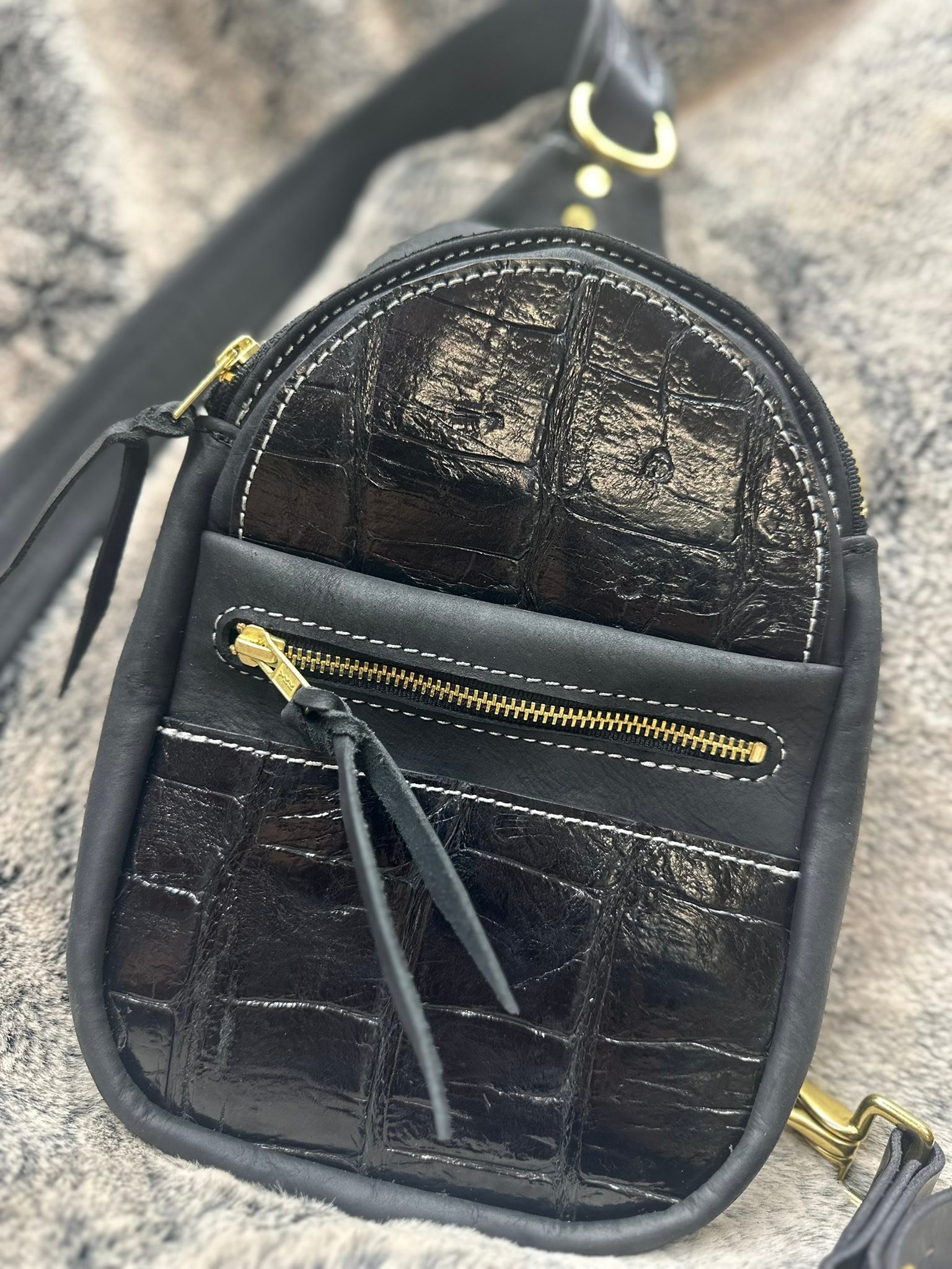 
Gigantic reptile shit: (this is the last of our mini sling bags in our holiday sale drop).
This bag has all the bling. Cut from a monster 12’ Florida gator that rivals anything you’ve seen on Swamp People—and yeah, those 2” tiles are the evidence. Dead center on the top panel? Two completely healed scars from an even larger gator attack, because apparently this thing survived a bar fight with Godzilla before we turned it into a bag.
Black-on-black gator front panels, in a high gloss finish, paired with smooth black Muddy River veg-tann, white contrast stitching, and solid brass hardware that’s not gonna quit on you halfway through a Walmart run.
Unlike me, this bag has its shit together.
Details, because details matter:
• Three front pockets — yeah, three — one of them zippered so your stuff doesn’t go bouncing off into the abyss
• Inside pocket for the important shit
• Adjustable strap
• Solid brass hardware
• Even the YKK brand zippers are made in the USA
• Handmade, one at a time, by a human.
Now let’s talk money. This is one of the most expensive pieces on our website at $1,300. Right now? Insanely discounted to $800.
Sale ends Christmas Day at noon. No that’s not a typo. That’s me making space and you winning.
And before you ask — FREE Priority shipping anywhere in the USA.
No surprise fees. No “handling charge” nonsense.
⚠️ Christmas warning:
If you want this under the tree instead of explaining, “Yeah, it was cool online but it didn’t get here in time,” you need to move. Once this ships, it’s gone, and there isn’t another one hiding in the shop.
One bag. One shot.
When it’s gone, it’s gone.
