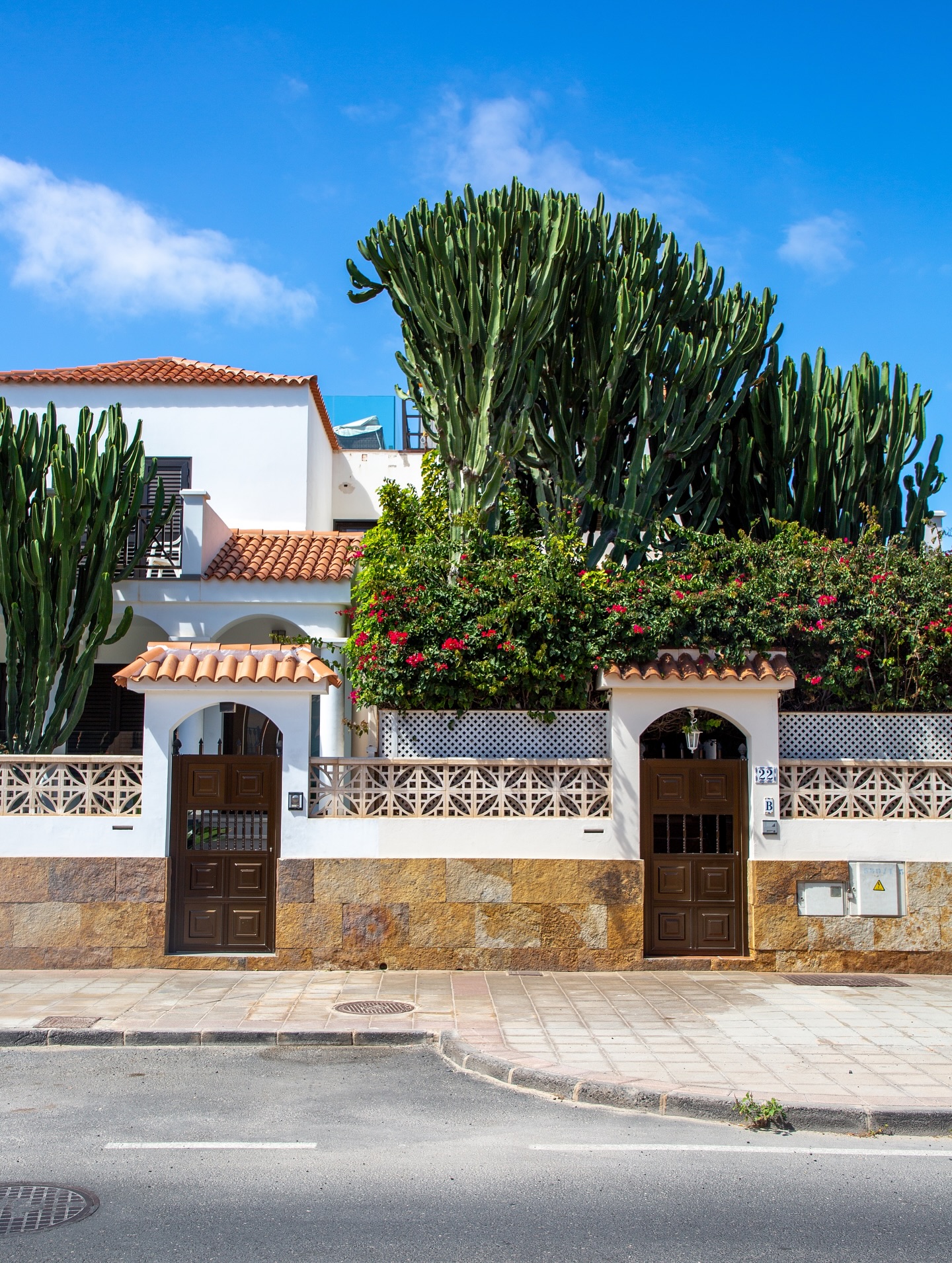 Squeals of kids jumping across the dunes, kicking up clouds of dust with their heels.
Wind whipping against cheeks, carrying the scent of the sea in shades of choppy turquoise below.
Whitewashed villages with emerald green painted window panes chipping dry in the searing sun.
Summer-bleached terracotta roofs.
Endless slopes rolling across the land.
Volcanic.
Surreal.
Bare.
A natural sculpture that stretches to the horizon where the ocean pounds against the shore.
Wide-open spaces.
Baked under the heat.
Stark beauty.
Silence.
Long stretches of road with no traffic.
Windmills.
Cacti.
Rocks.
Tufts of dry plants where goats graze.
Single palm trees stretching high into a brilliant blue sky.
Each village marked with big white letters that the kids climb on: Betancuria. La Oliva. Antigua.
This is Fuerteventura.
The oldest of the Canary Islands.
Once a place of exile for Spanish write Miguel de Unamuno who described it as “a skeleton of land.”